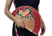 Cargar imagen en el visor de la galería, Vivaz Blau Almería con mucha luz y color. La combinación de flores rojas y amarillas pálidas junto con el contraste de la tela de algodón hacen de este producto un abanico muy fino que acompaña genial con vestidos de colores muy definidos que aportan sintonía y contraste con el color de la tela y complementos dorados.
